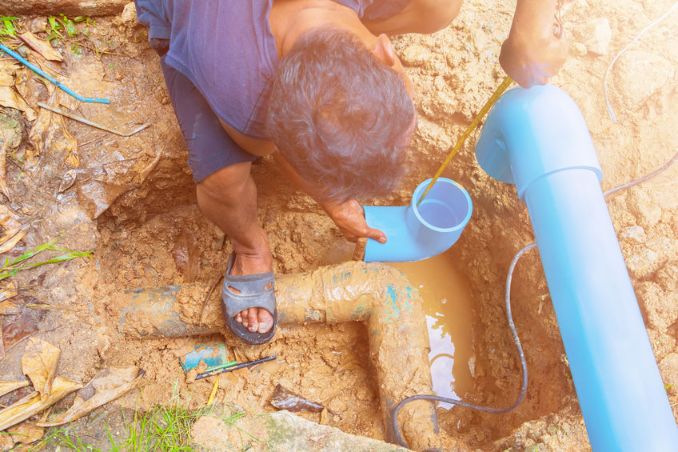 Sewer repair technician measuring pipe for outside installation