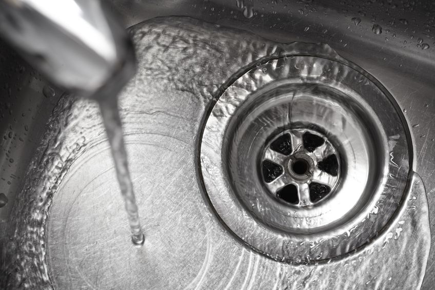 Water running smoothly down drain in stainless steel sink