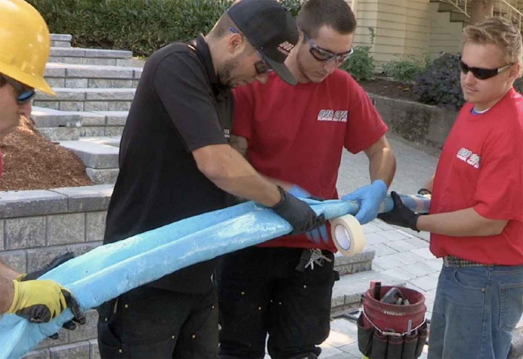 Bob Oates technicians holding pipe, doing pipe lining work before installation