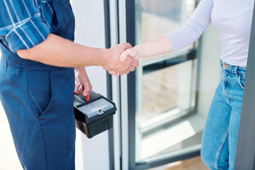 Young woman and technician with toolbox saying goodbye while shaking hands after repair work