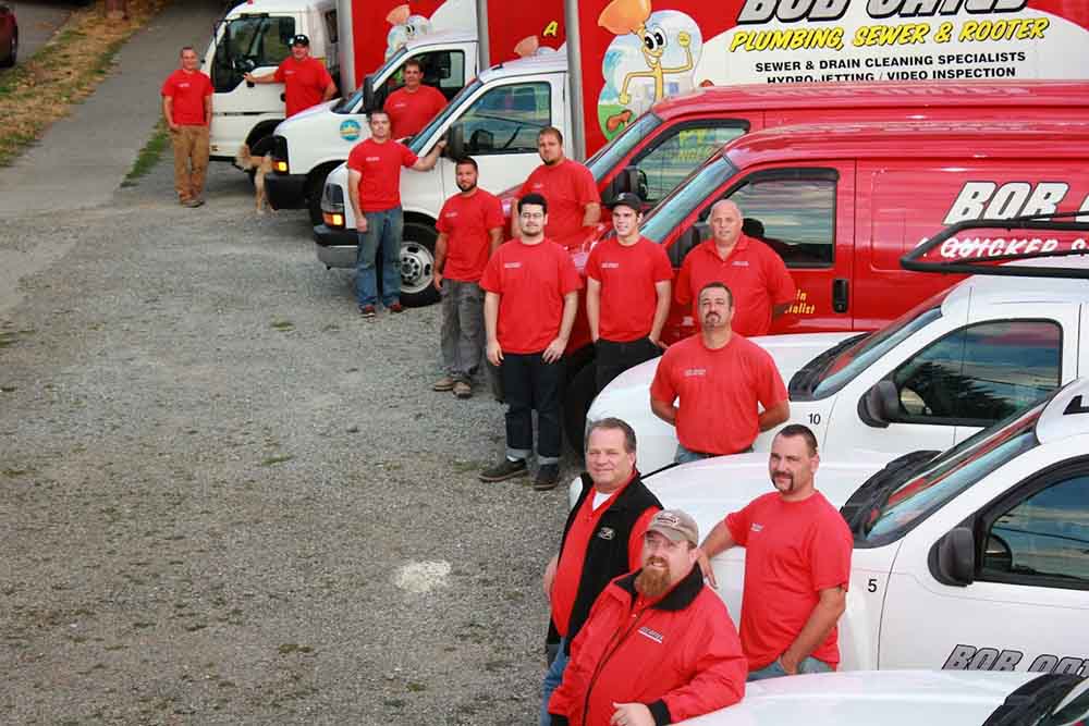 Bob Oates technicians standing by their trucks outdoors