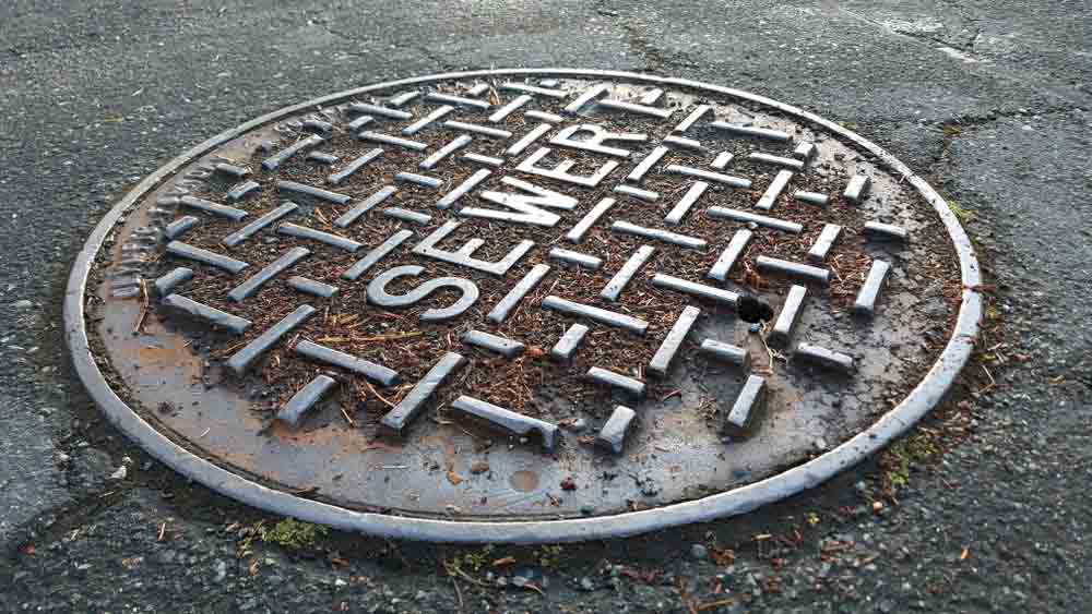 Close up of sewer metal cap on the road after rain