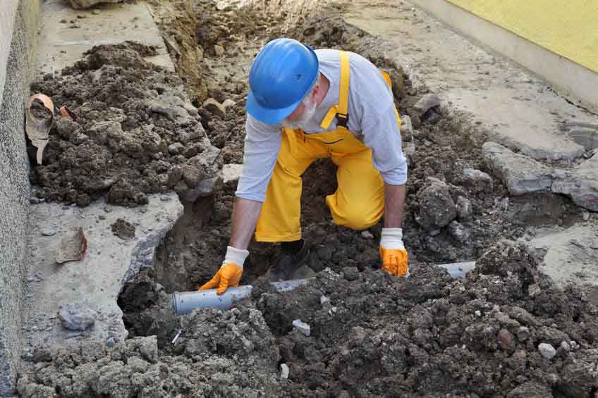 Sewer technician at construction site repairing sewer pipe