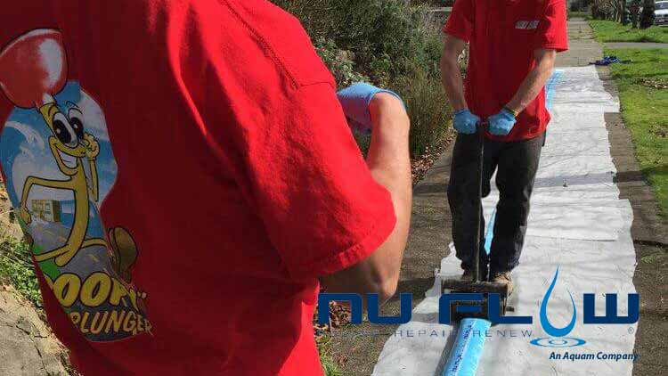 Two Bob Oates techs displaying how the pipe lining process works