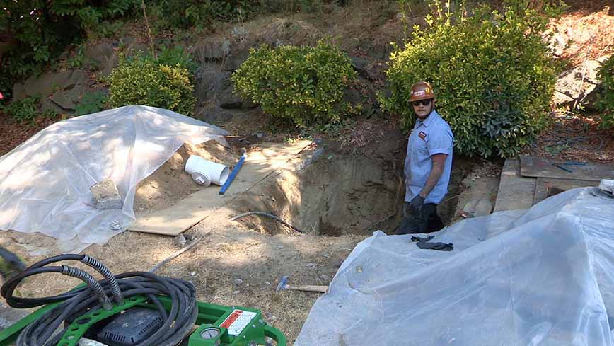 Sewer tech standing in hole about to do repair work