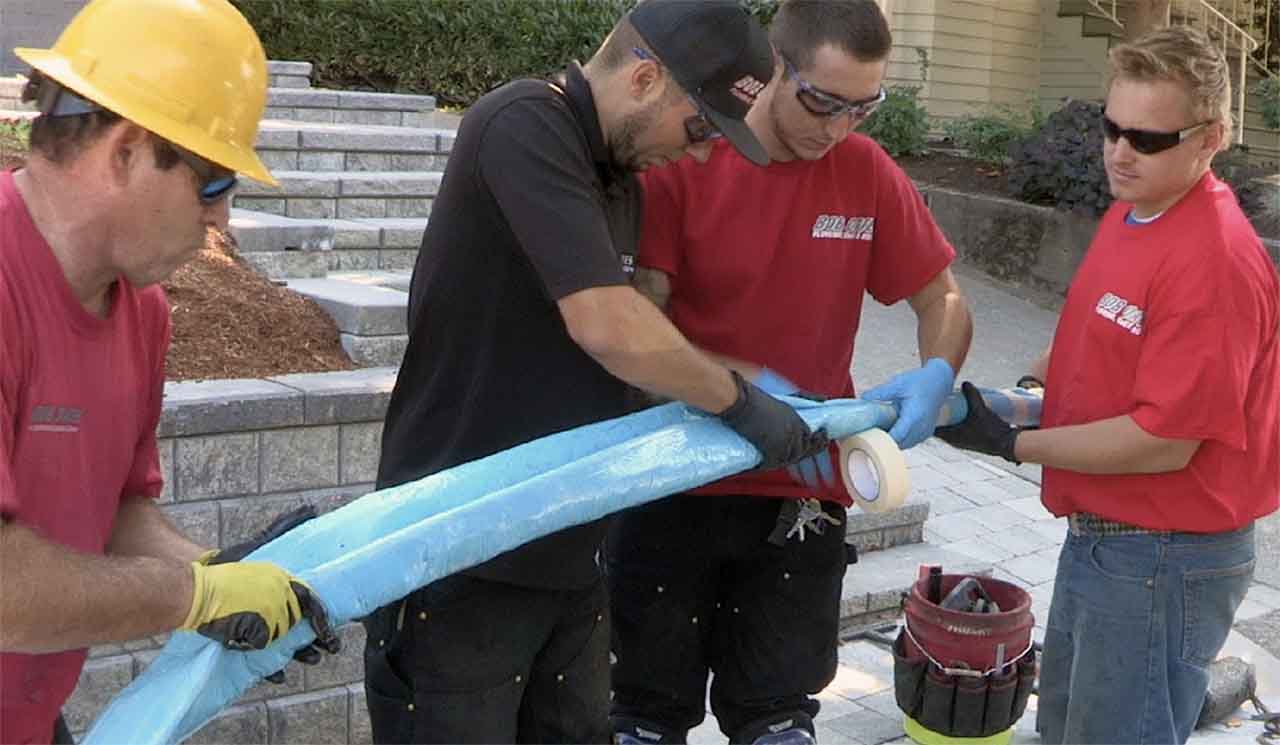 Bob Oates technicians holding pipe, doing pipe lining work before installation