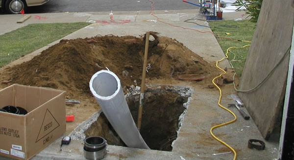 Near sewer pipe sticking out of the ground, about to be installed going trenchless