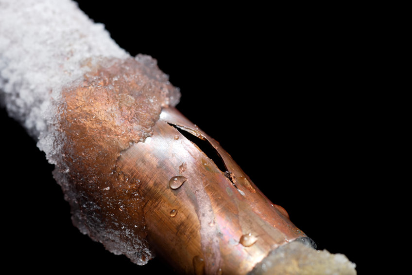 Cracked copper pipe with ice on it, damaged from freezing