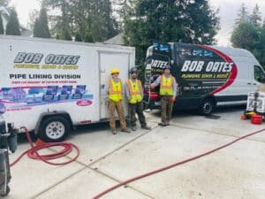 Bob Oates Plumbing, Sewer & Rooter crew standing in front of company service trucks during a residential sewer relining job in the Seattle area.