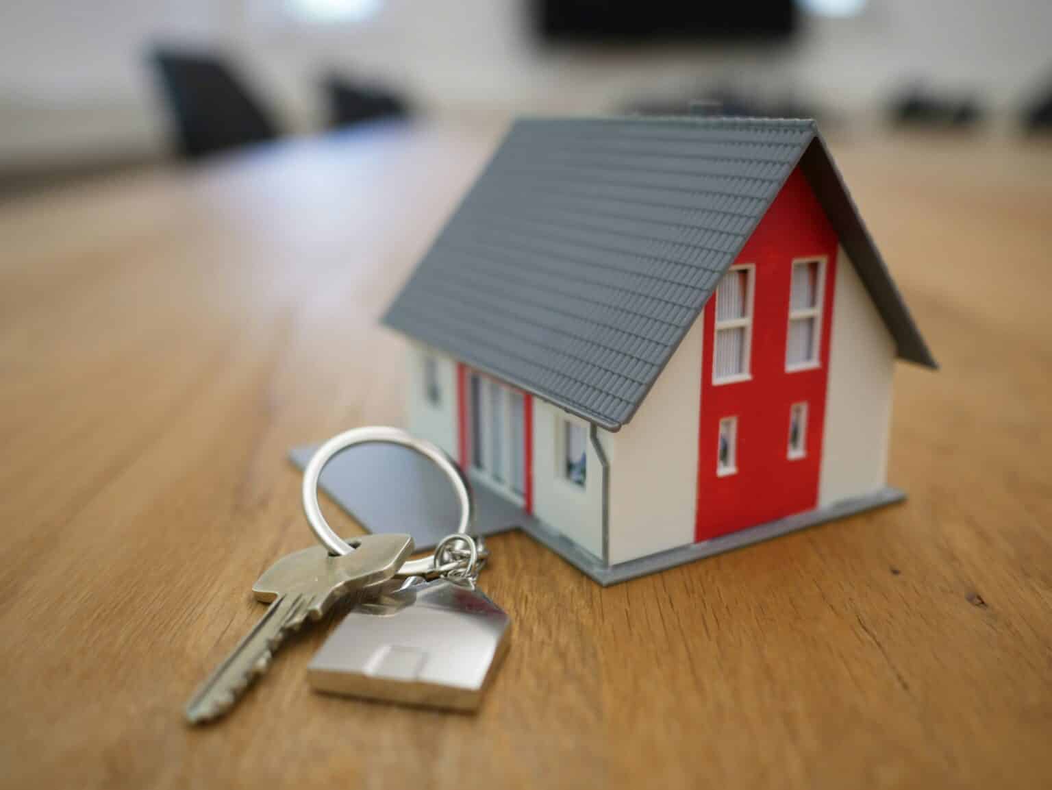 Model house and key on table, representing home ownership or real estate purchase