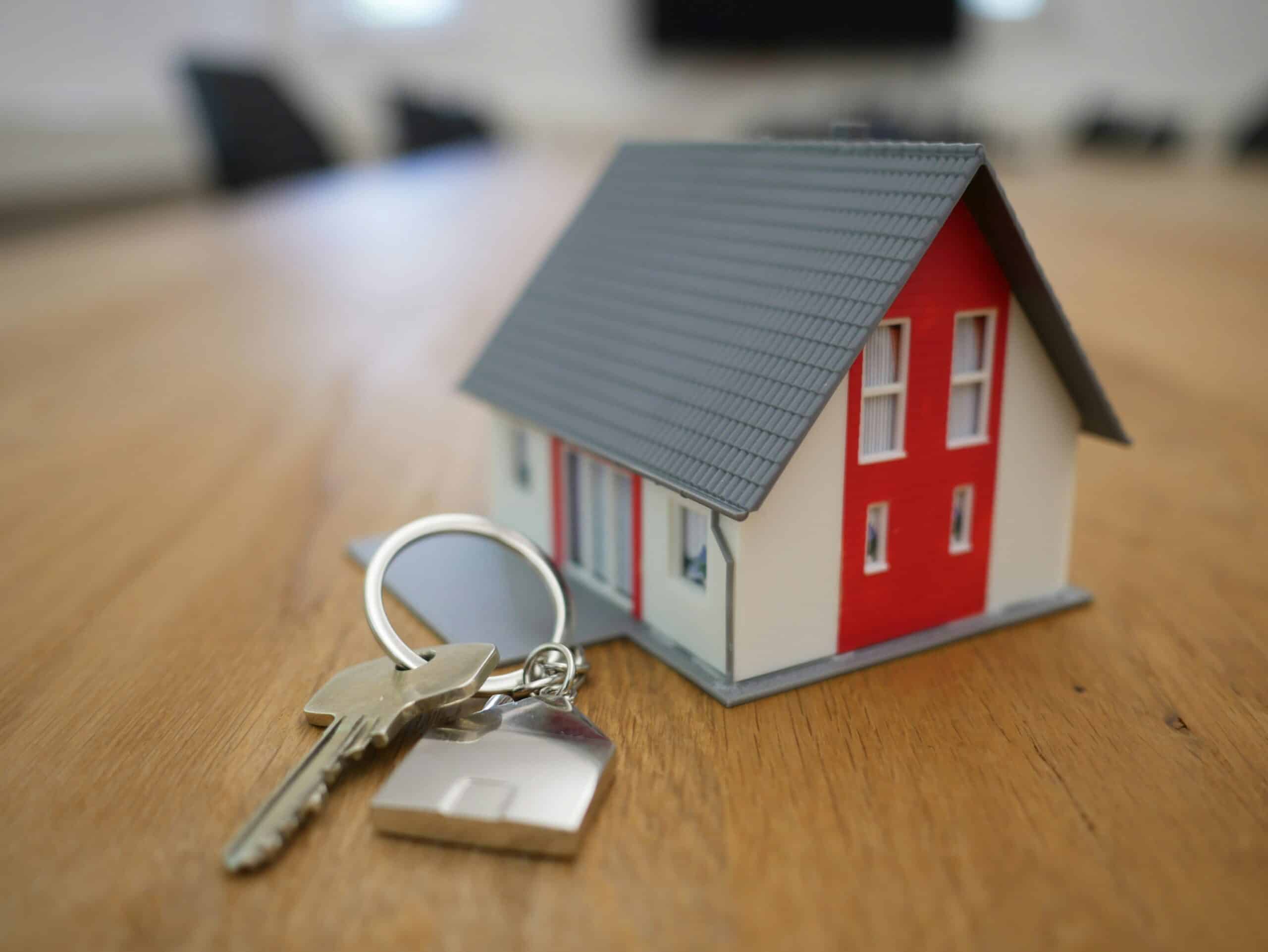 Model house and key on table, representing home ownership or real estate purchase