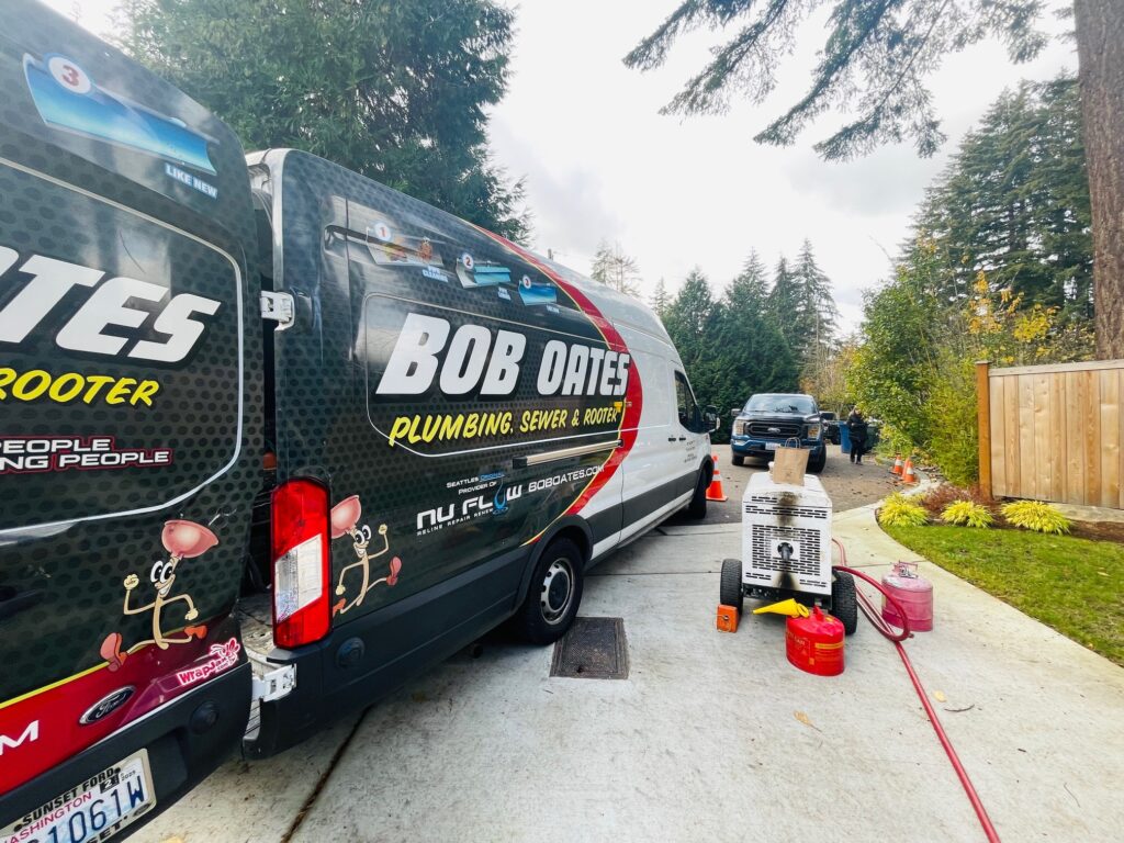 Bob Oates Plumbing, Sewer & Rooter van parked at a residential job site in the Greater Seattle Area, with sewer repair equipment set up nearby.