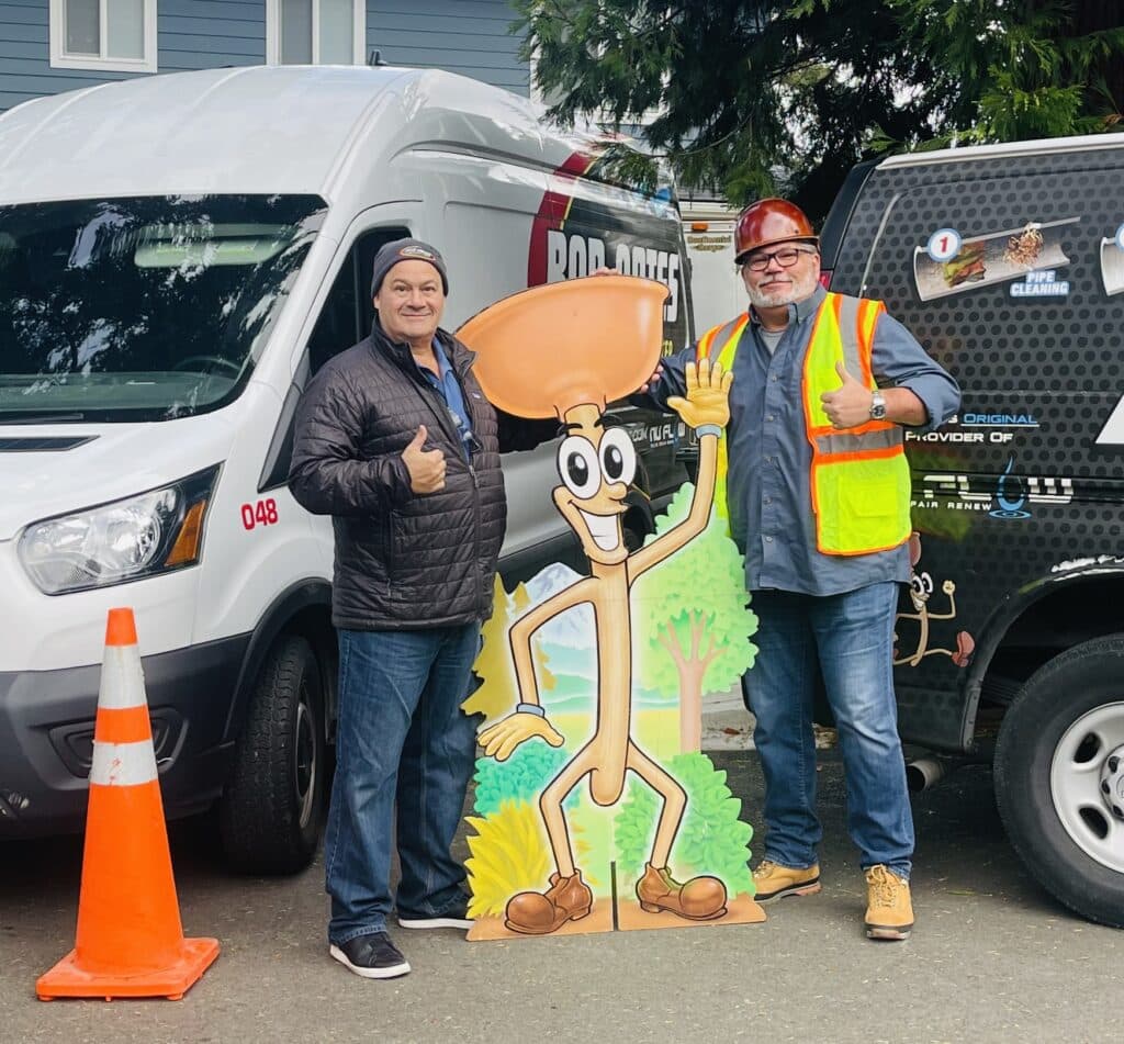 Bob Oates and general manager John Peterson posing with Poopy the Plunger mascot in front of Bob Oates service vans