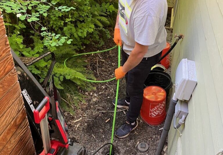 Bob Oates technician hydro jetting a sewer line through an outside cleanout at a Seattle home