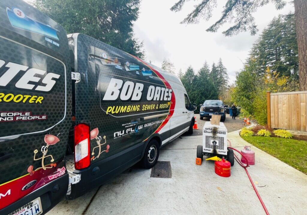 Bob Oates Plumbing, Sewer & Rooter van parked at a residential job site in the Greater Seattle Area, with sewer repair equipment set up nearby.