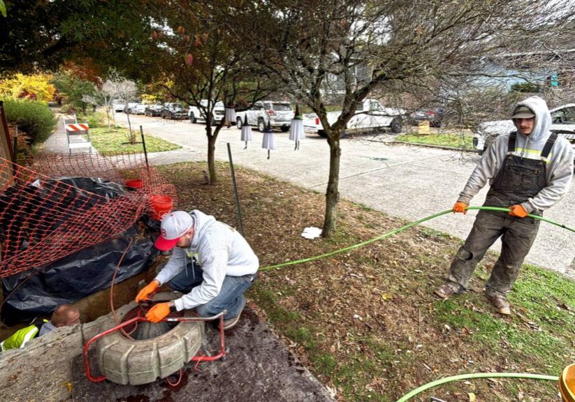 Professional plumbers preparing hydro jetting equipment to clean a residential sewer line