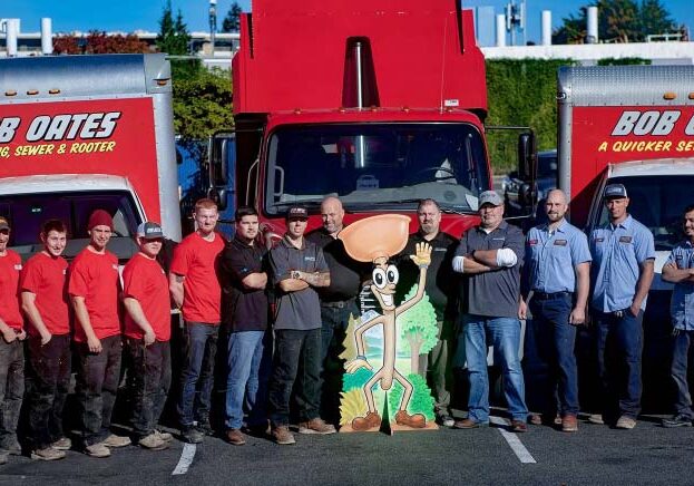 Group photo of of Bob Oates technicians standing in front of company trucks