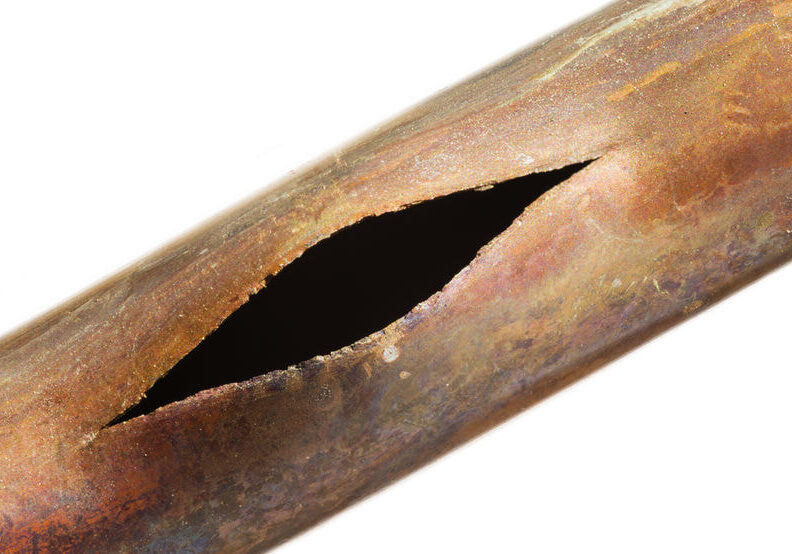Close-up of a cracked plumbing pipe damaged by corrosion and wear