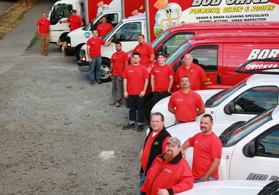 Bob Oates technicians standing by their trucks outdoors